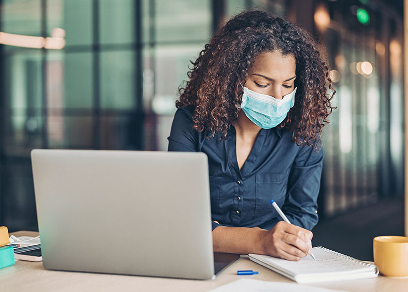 Woman with mask using laptop